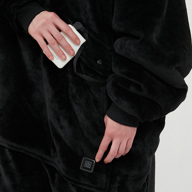 Close-up of a power bank going into a pocket on the hoodie blanket, with the power button near the hem