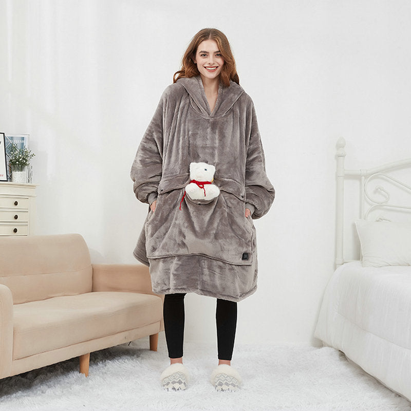 Woman wearing the grey Hoodgrove heated hoodie blanket with a teddy bear in the front pocket
